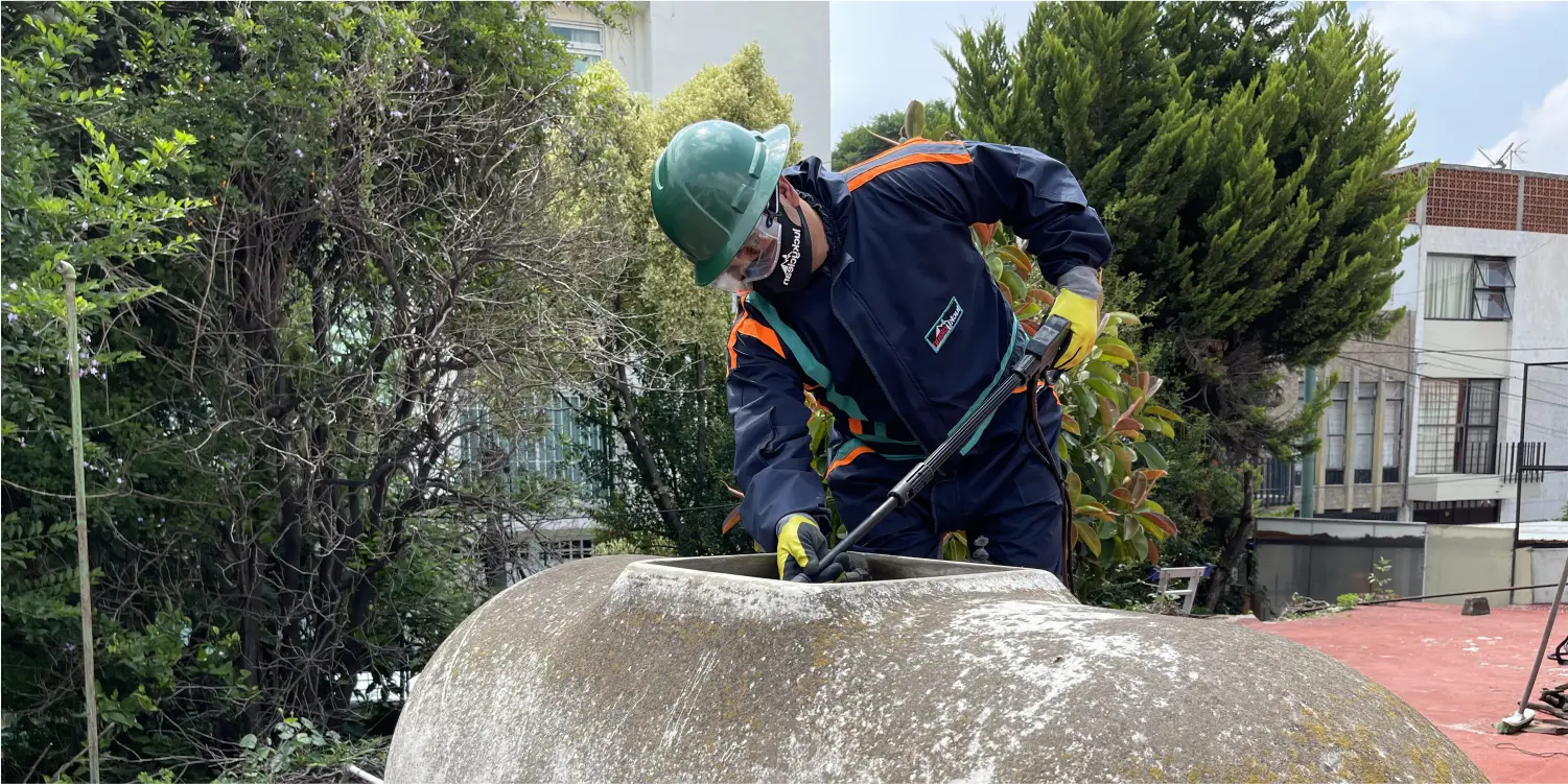 Operador realiza un enjuague a tinaco de asbesto durante el lavado de tinacos en Zumpango