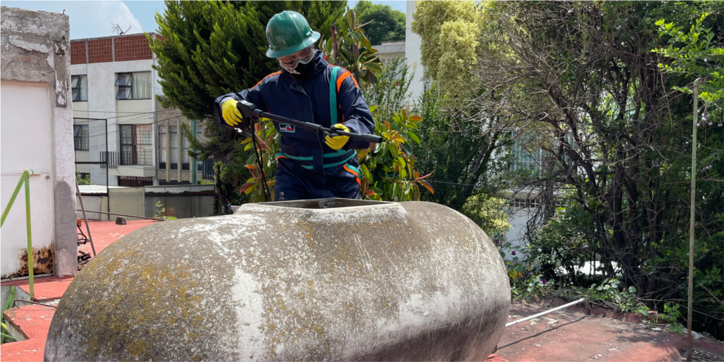 Operador realiza enjuague a tinaco de asbesto durante la limpieza de cisternas y tinacos en Nezahualcóyotl
