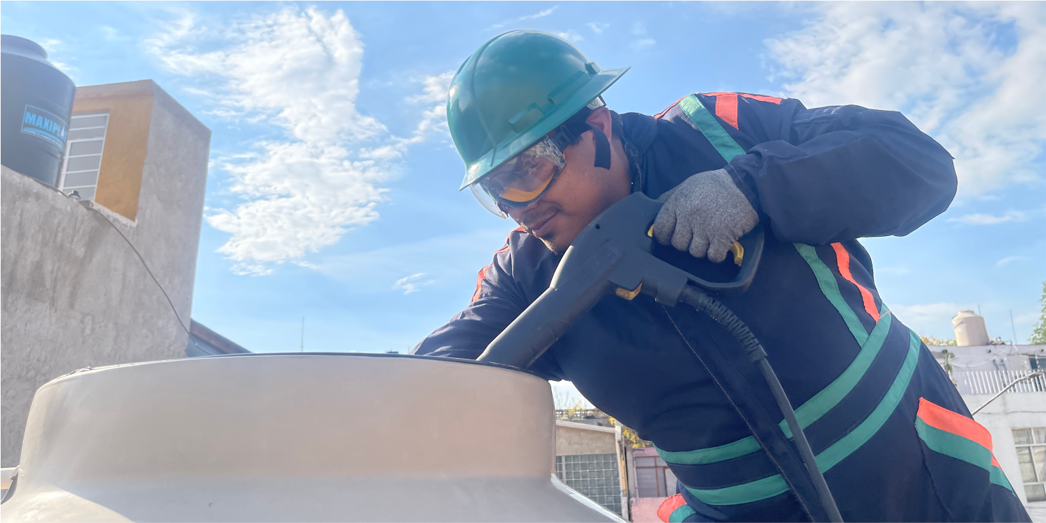 Técnico realiza el enjuague a un tinaco durante la limpieza de cisternas y tinacos en Naucalpan